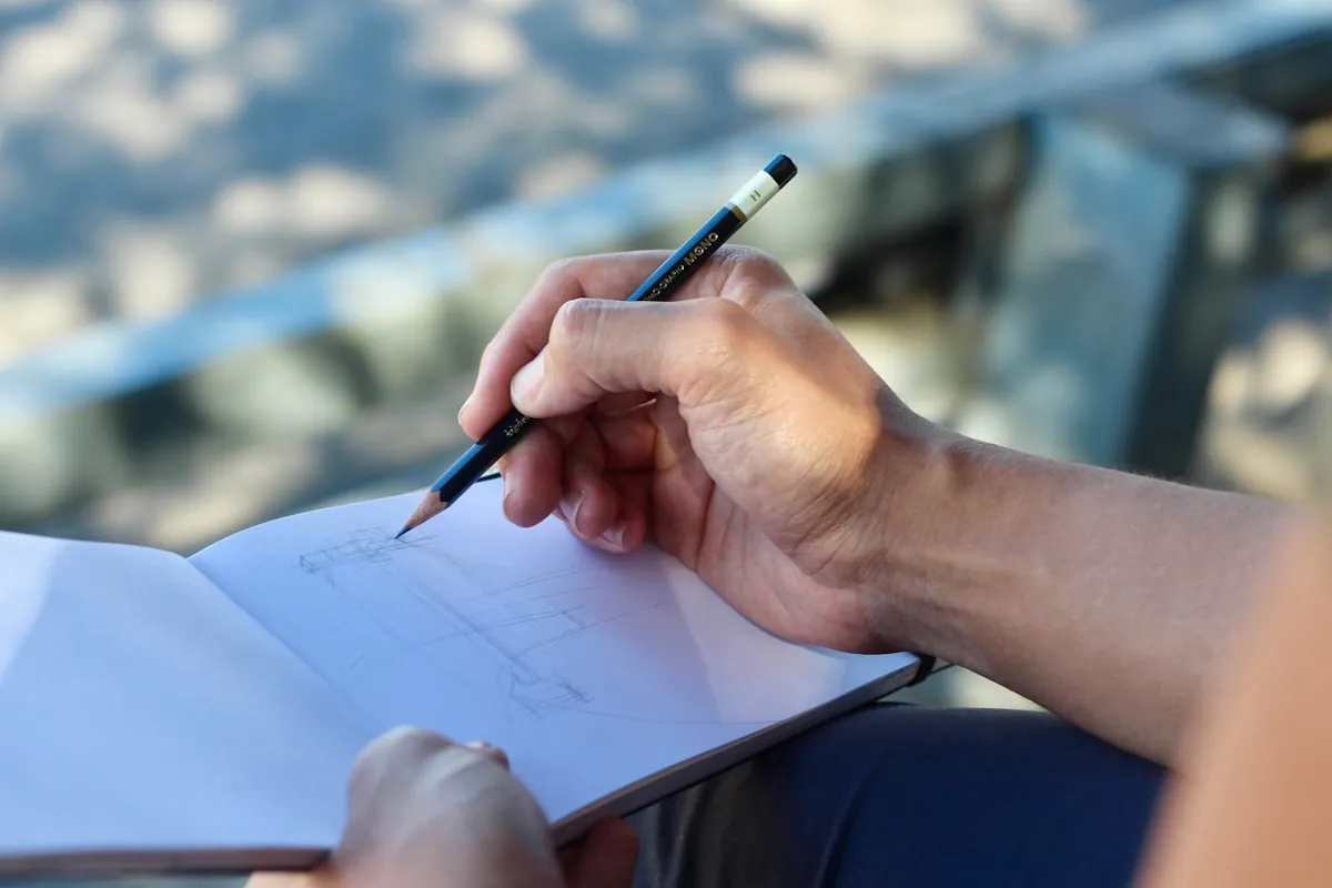 Personne qui dessine un croquis sur un carnet blanc